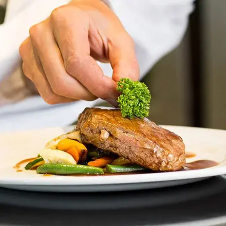 Hudson Estates Chef Created Meals, chef garnishing a plate.